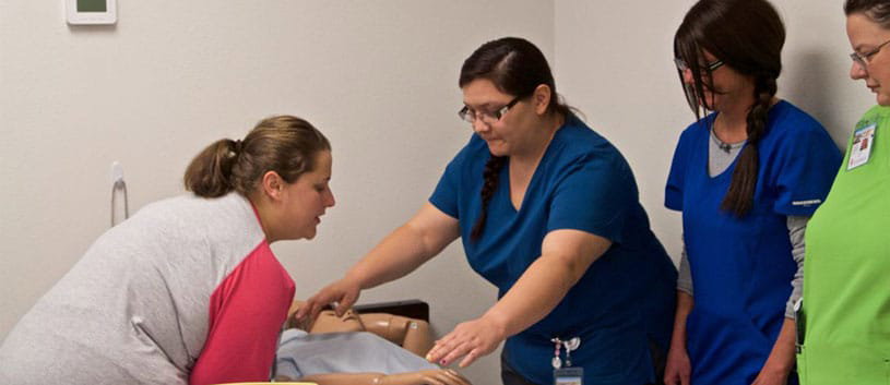 IntelliTec College Nursing Assistant students practice on a dummy