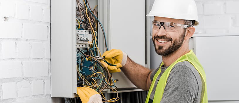 Male electrical technician working on a wire box. 